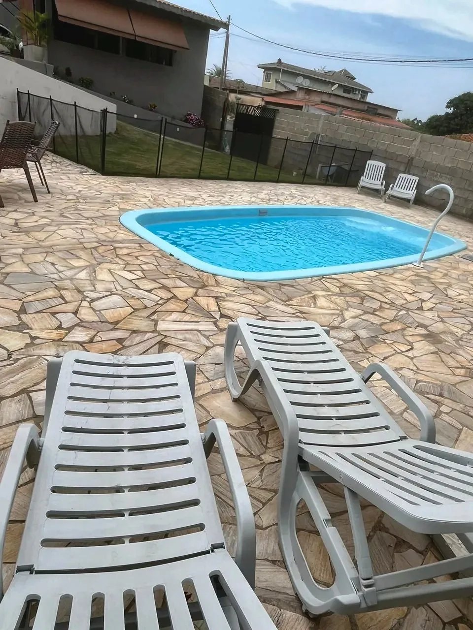 Piscina privativa com espreguiçadeiras e piso de pedra