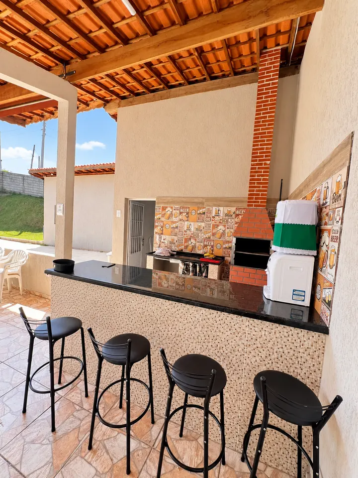 Balcão com banquetas e churrasqueira de tijolos na área gourmet