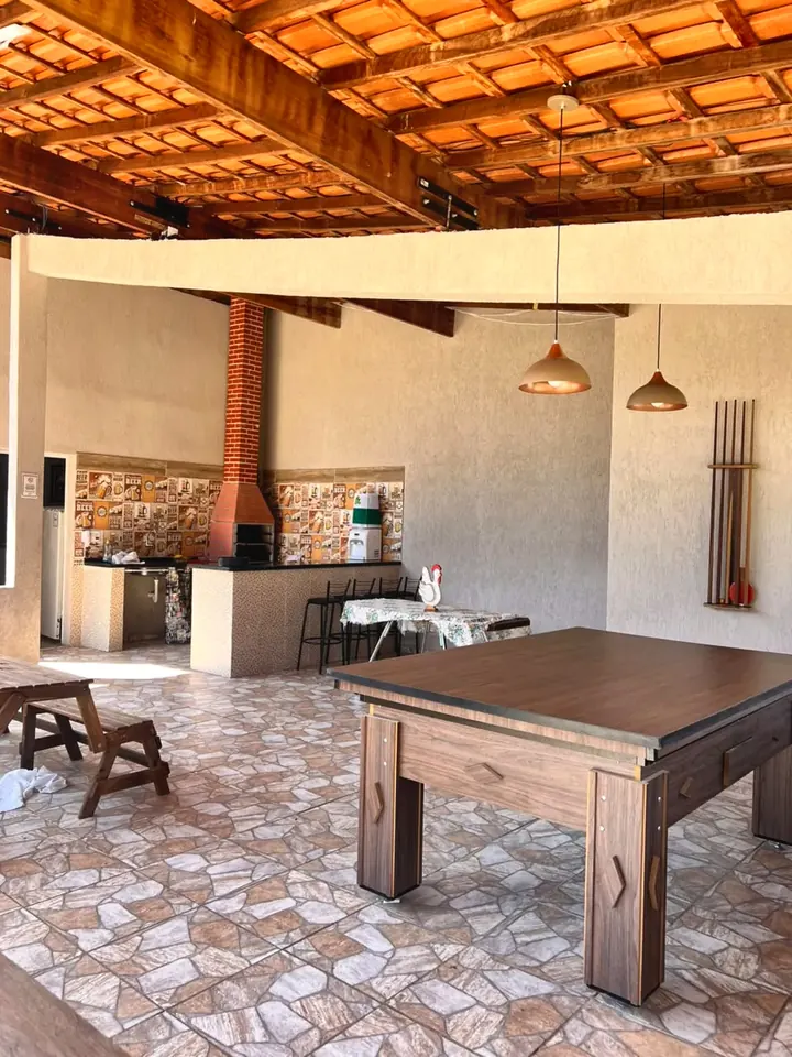 Mesa de sinuca na área gourmet, com a churrasqueira ao fundo
