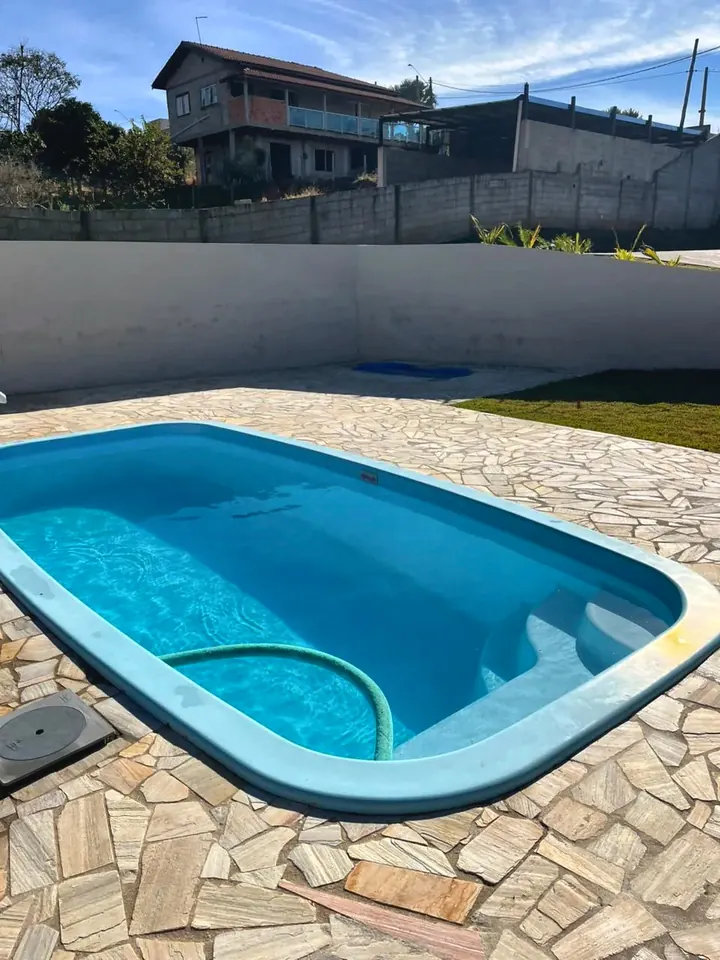 Piscina em dia de sol, com o piso de pedra ao redor